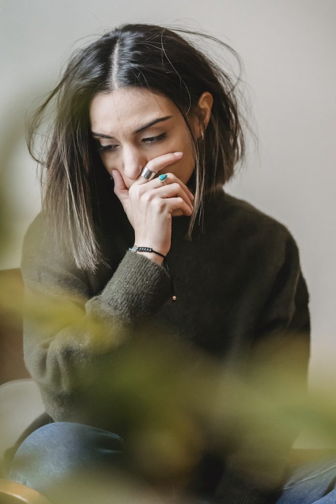 Lady crying with hand on mouth in room